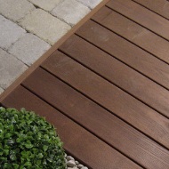 Vue détaillée d’une terrasse en bois dur à côté d’une plante verte avec jardin de rocaille